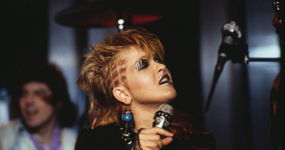 Cyndi Lauper, U.S. singer-songwriter, singing into a microphone, silver make-up on her lips and eyelids, at the Montreux Rock Festival, in Montreux, Switzerland, May 1984. (Photo by David Redfern/Redferns/Getty Images)